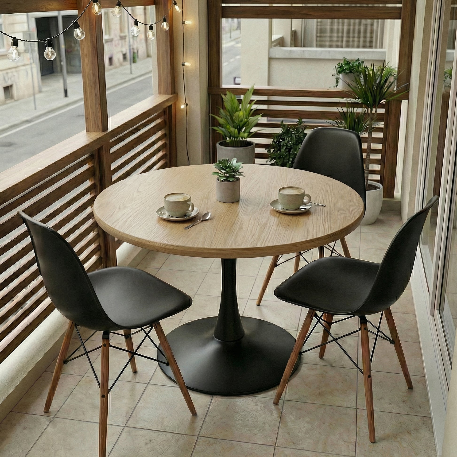 Round wooden table with black chairs on a balcony with plants and string lights.